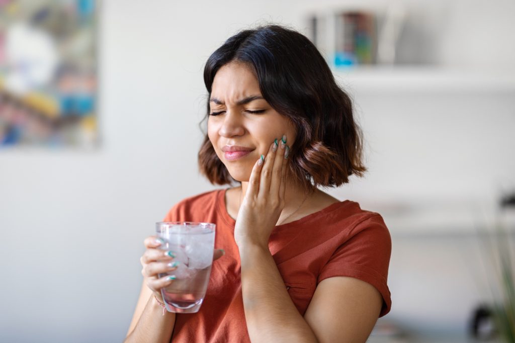 Patient experiencing tooth sensitivity while drinking a cold beverage in Leawood, KS